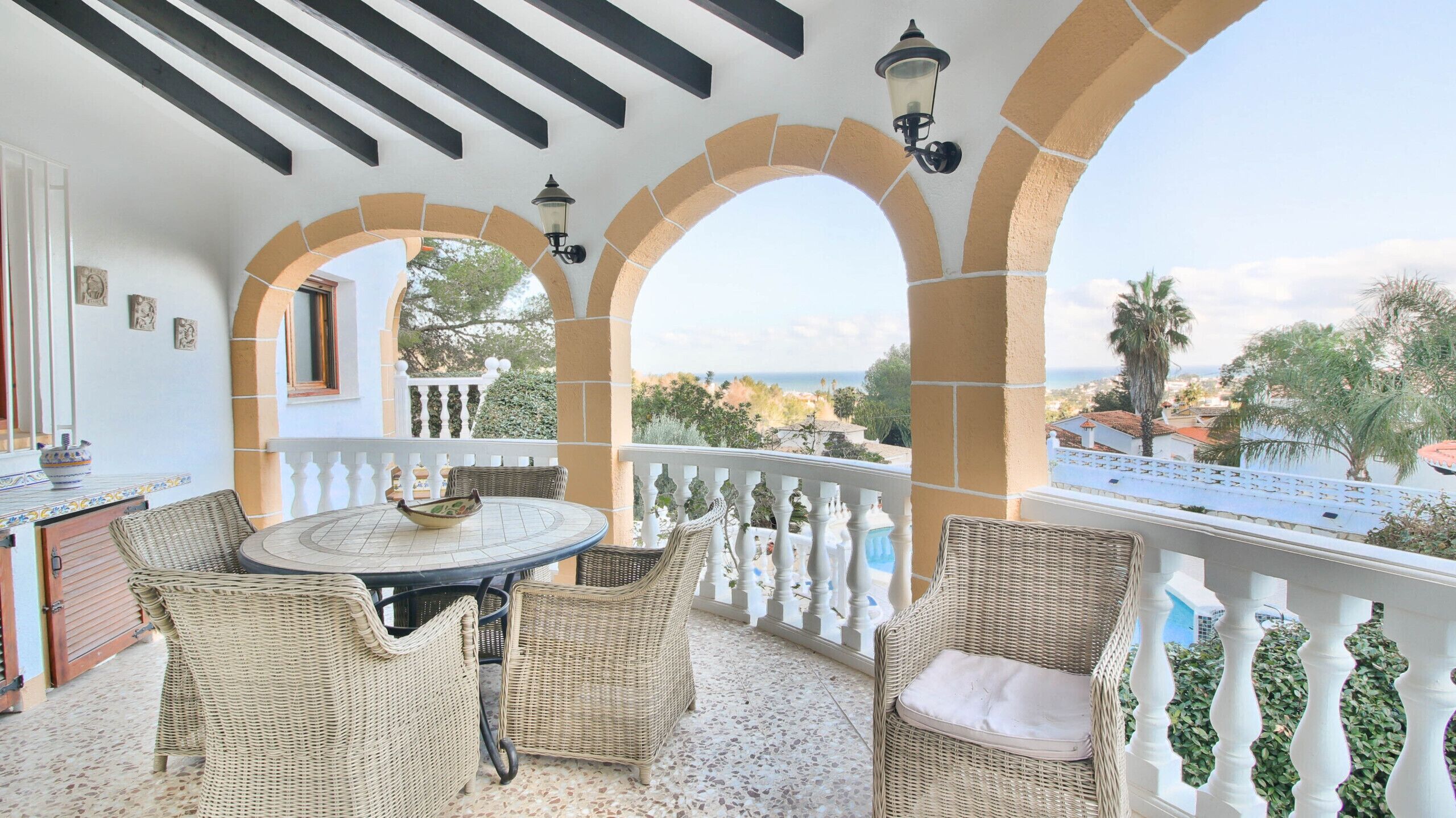 Ein Balkon mit Korbmöbeln, einem runden Tisch und Meerblick.
