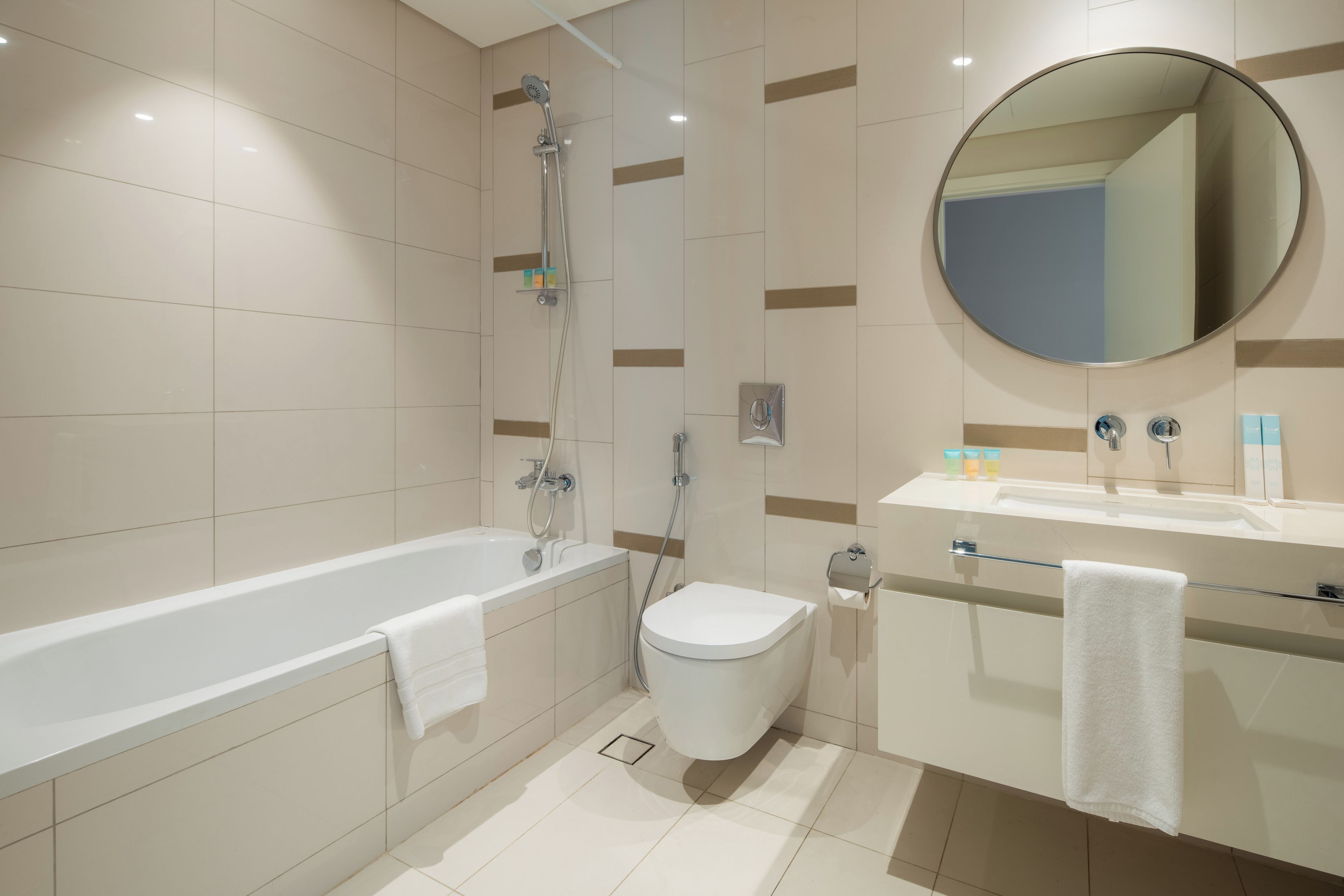 Een moderne badkamer met een bad, toilet en wastafel.