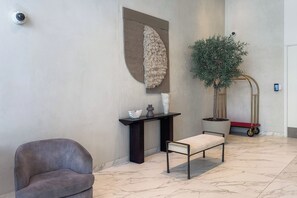 A modern lobby with a seating area, a decorative wall, a plant, and a security camera. - Beachfront Living with Marina Skyline Views (Dubai)