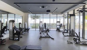 Ein modernes Fitnessstudio mit unterschiedlichen Trainingsgeräten, großen Fenstern und Blick ins Freie.