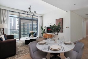 Ein modernes Wohnzimmer mit Essbereich, großen Fenstern, einem Flachbildfernseher und Blick auf die Stadt.