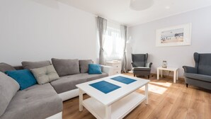 Ein modernes Wohnzimmer mit einem grauen Sofa, einem weißen Couchtisch und einem grauen Sessel.