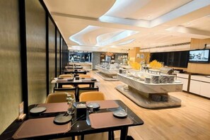 Un interior de restaurante moderno con mesas, sillas, una isla central y una pantalla de televisión.