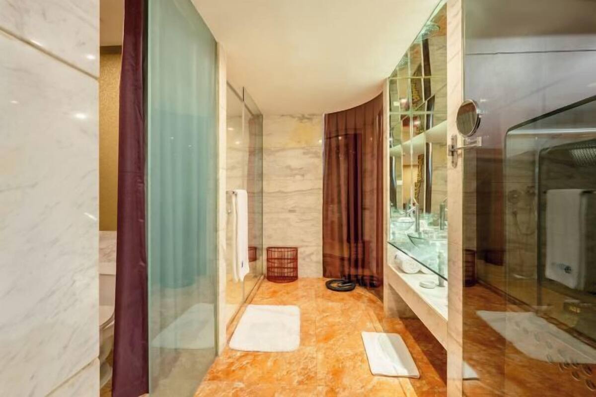 Un baño moderno con cabina de vidrio, suelo de mármol y zona de ducha acristalada.