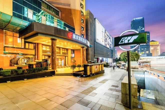 A modern hotel with a prominent entrance, a well-lit lobby, and a view of the surrounding cityscape.