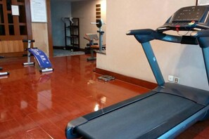 Un gimnasio con cinta de correr, equipamiento de ejercicio y suelo pulido.