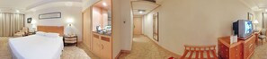 Una habitación de hotel con cama, escritorio, televisor y armario.