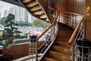 Una escalera de caracol con escalones de madera y barandales de metal, que conduce a un piso superior.