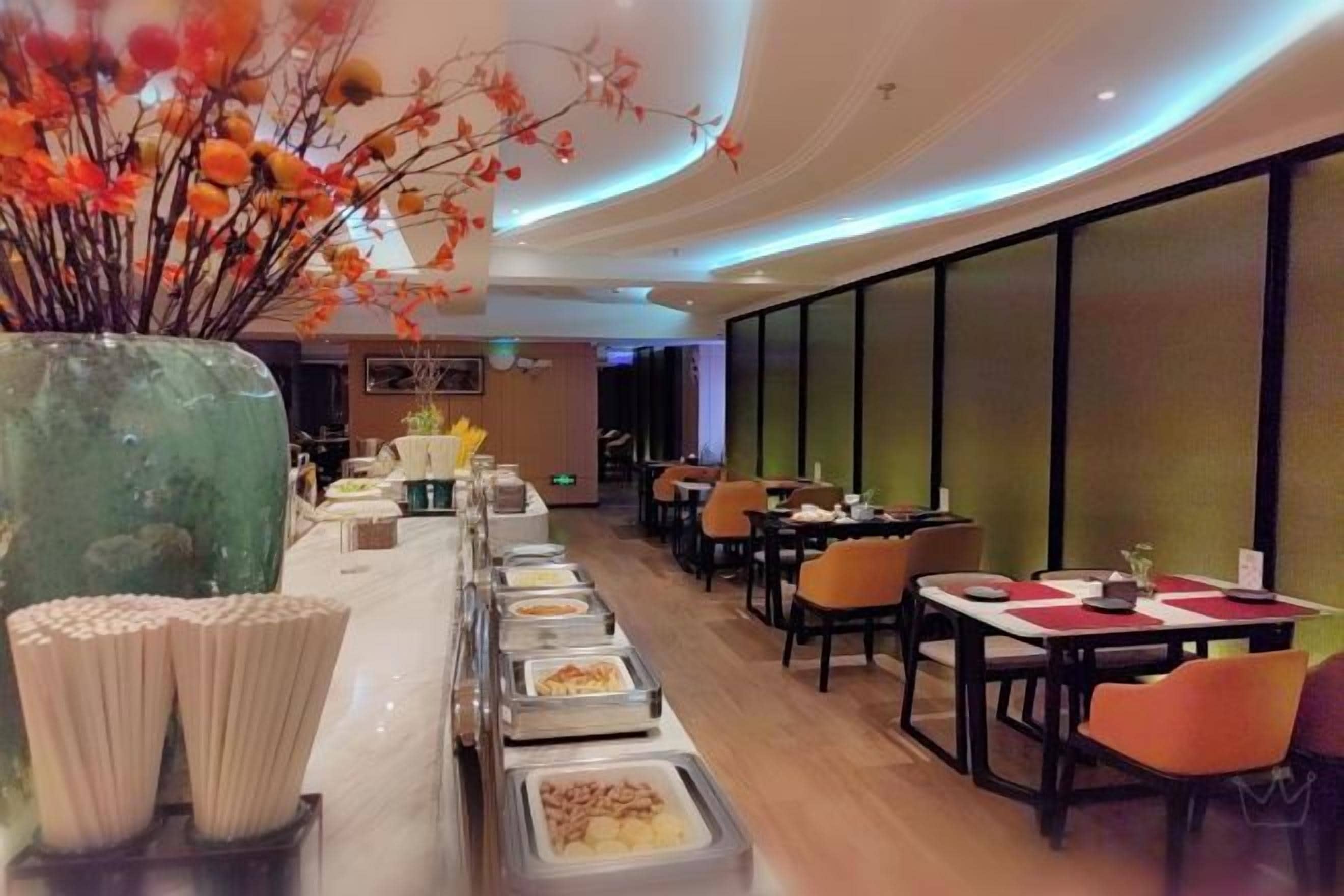 A restaurant with a long buffet line, tables, and chairs.