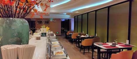 A restaurant with a long buffet line, tables, and chairs.