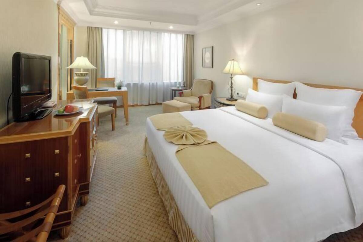 Habitación de hotel con una cama grande, un escritorio con televisor y dos sillas.