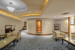Un vestíbulo de hotel con techo curvo, una columna central y zonas de estar.