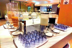 Een buffetopstelling met diverse voedingsdispensers en een schaal lege bekers.