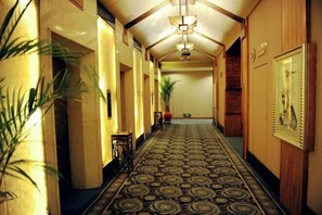 A hallway with patterned carpet, wooden paneling, and a large plant. - Chongqing Air China Hotel (Guanyin Bridge Branch) (Chongqing)