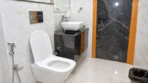 A bathroom with a white toilet, a sink, and a shower. - The Ora Hotel (Vrindavan)