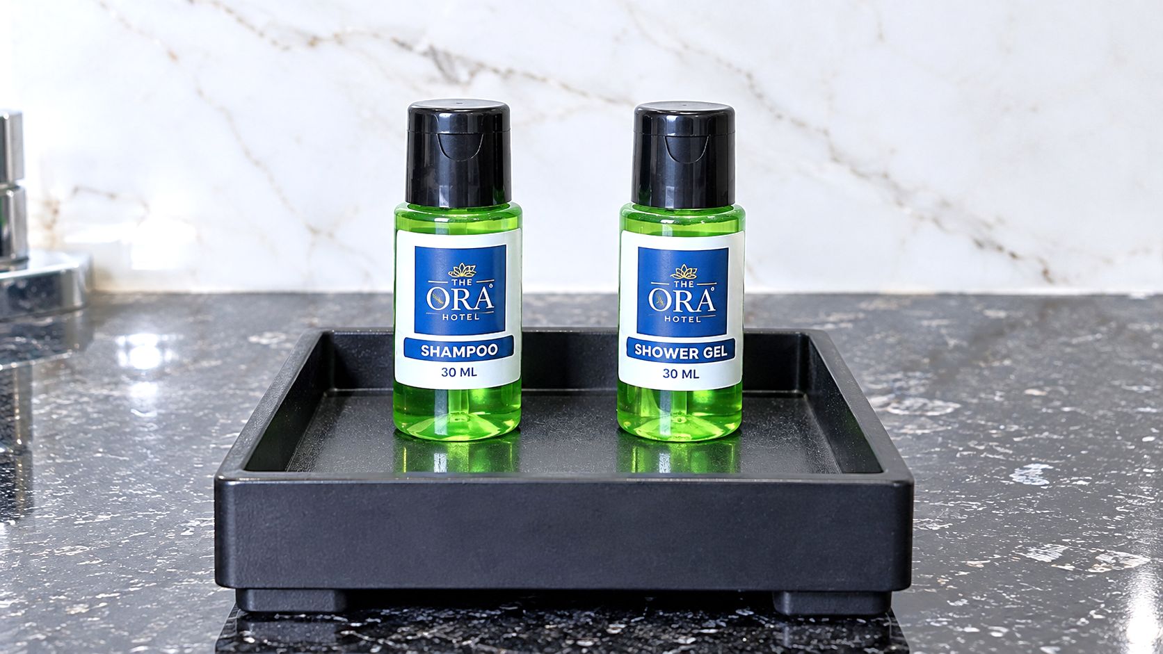 Two bottles of ORA Hotel shampoo and shower gel on a black tray.