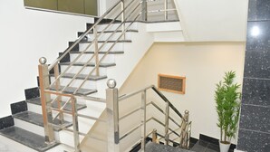 Un escalier avec des rampes en métal et un pot de fleurs placé à côté.