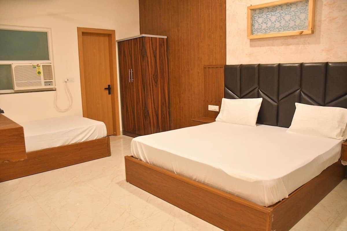 Un dormitorio con una cama grande, una cama más pequeña, un armario y un aire acondicionado instalado en la pared.