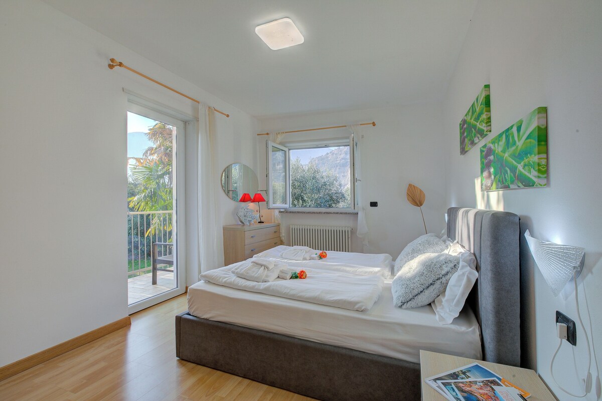 Ein Schlafzimmer mit Bett, Fenster, Heizkörper, Nachttisch und Bildern an der Wand.