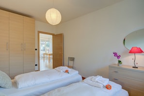 Ein Hotelzimmer mit zwei Betten, einem Holzschrank, einem Schreibtisch mit Stuhl, einem Spiegel und einer roten Lampe.