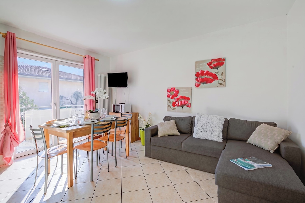 Ein Wohnzimmer mit Essbereich, einem grauen Sofa und einem an der Wand befestigten Flachbildfernseher.