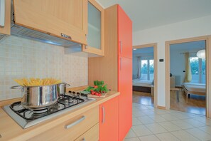 A kitchen with a stove, pots, and a window. - Agrilaura Apartments (Nago-Torbole)