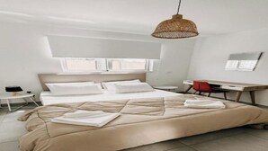 Une chambre moderne avec un grand lit, un bureau et un luminaire suspendu.