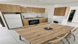 Une cuisine moderne avec des meubles en bois, un four encastré, un évier et une table à manger avec des chaises.