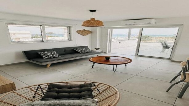Un salon moderne avec un canapé, une table basse ronde et un fauteuil en osier.