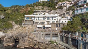Un edificio sul lungomare con diversi balconi, una facciata in pietra e vista mare.
