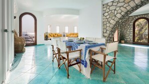 Un'ampia sala da pranzo con un arco in pietra, un tavolo imbandito con sedie bianche e vista sull'esterno.