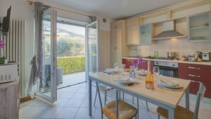 Cocina moderna con mesa de comedor para dos, vistas al exterior y puerta corrediza de vidrio que da a un balcón.