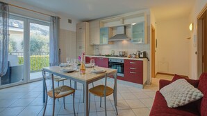 Una cocina moderna con comedor, un sofá rojo y un balcón con cortinas.