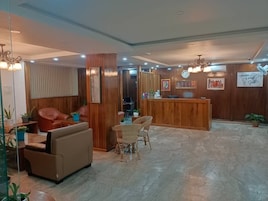 Un hall con mostrador de recepción, zona de estar y paneles de madera.