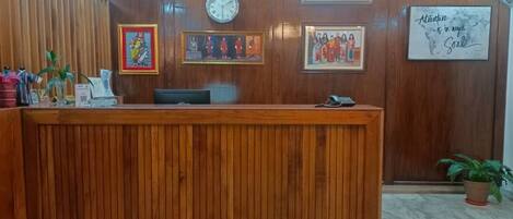 Un mostrador de recepción de madera con obras de arte enmarcadas en la pared, un reloj y una cita inspiradora.