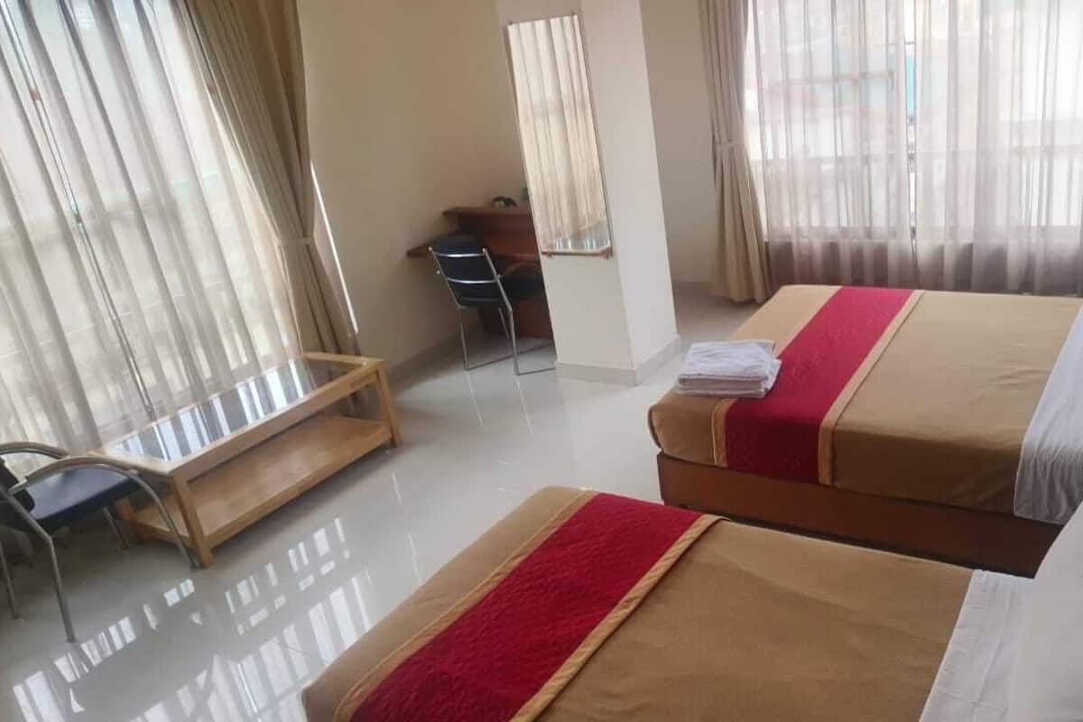 Habitación de hotel con dos camas, un escritorio y una silla.