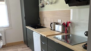 Une cuisine moderne équipée d’un lave-vaisselle, d’une cuisinière noire et d’un plan de travail en bois.