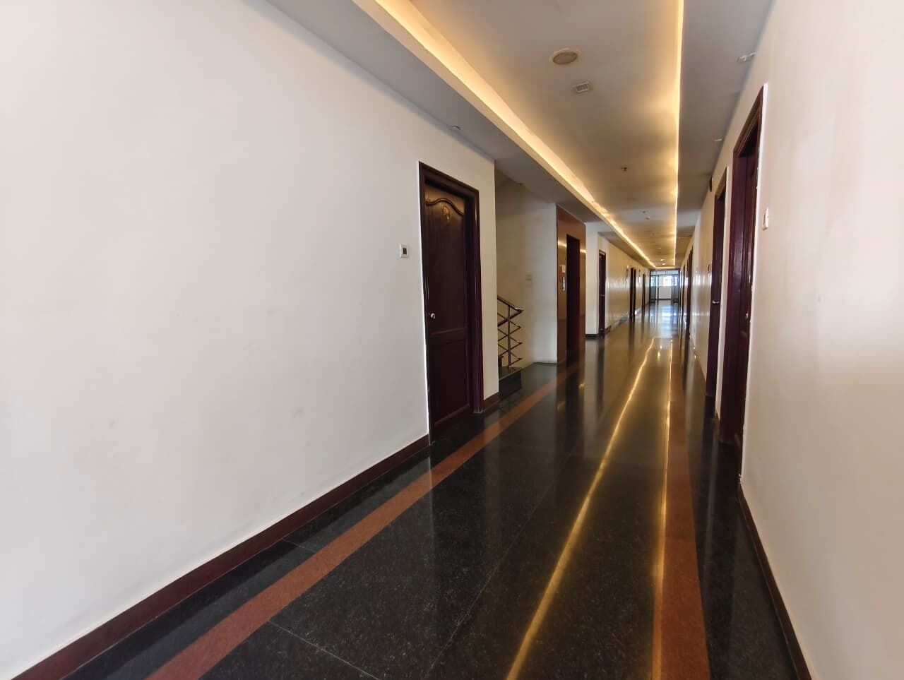 A long, well-lit hallway with doors on both sides, leading to multiple rooms.