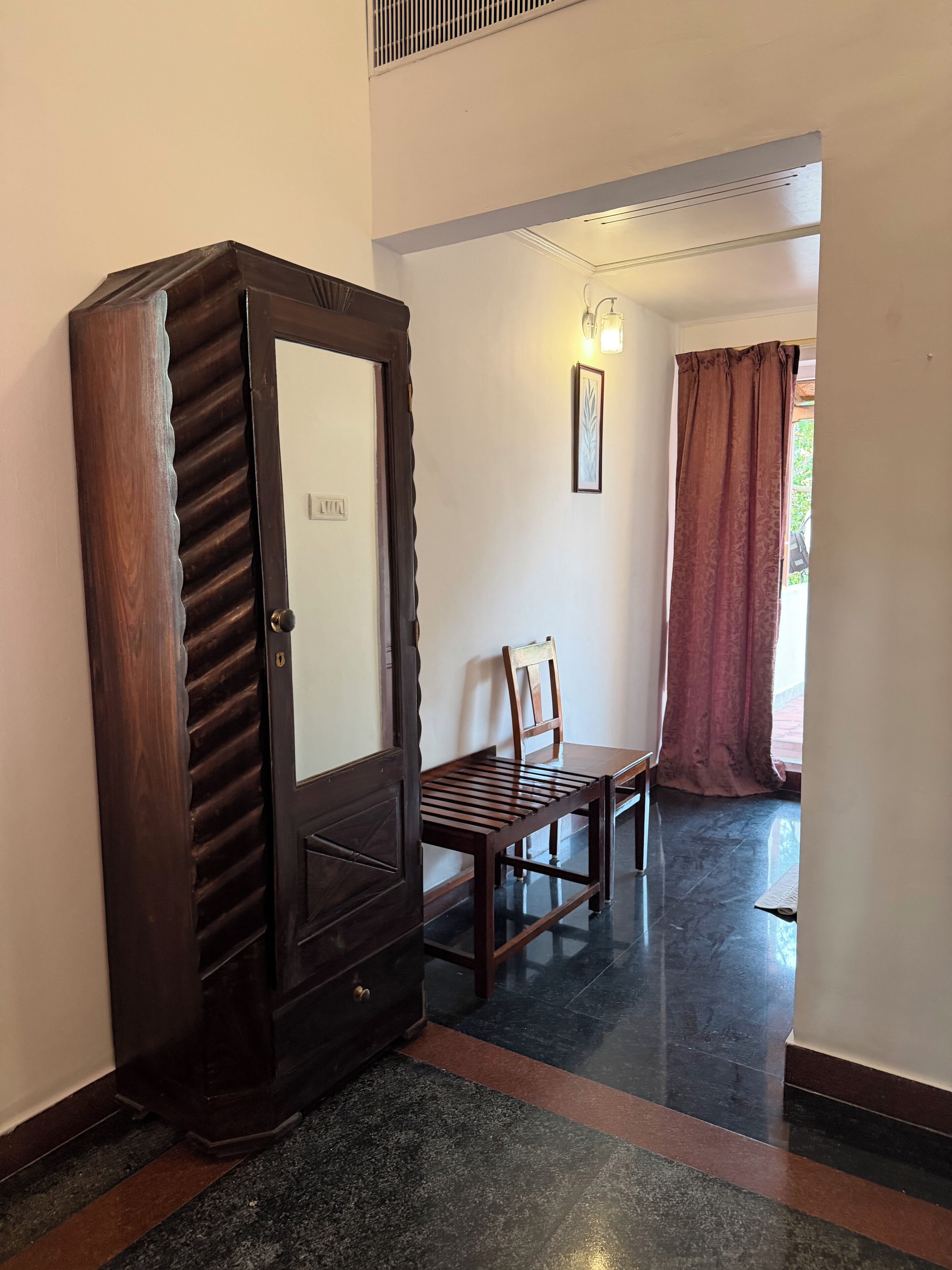 A hallway with a wooden wardrobe, a chair, and a table.