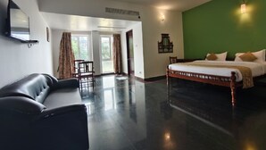 Ein Hotelzimmer mit Bett, Sofa, Fernseher, einer grünen Akzentwand und Blick durch die Tür.