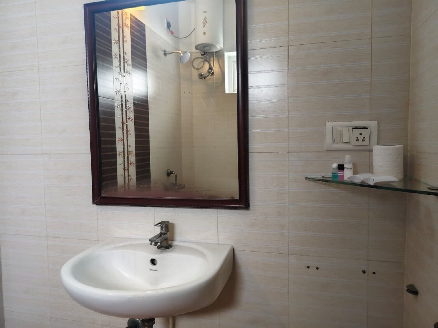 Een badkamer met een witte wastafel, een spiegel en een douche.