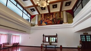 Ein geräumiger Saal mit hoher Decke, einem großen Fenster und einem dekorativen Gemälde.
