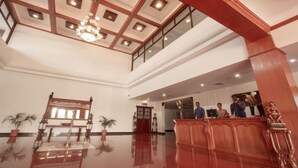 Eine geräumige Lobby mit hoher Decke, einem Empfangstisch und einer Kristallleuchtre.'