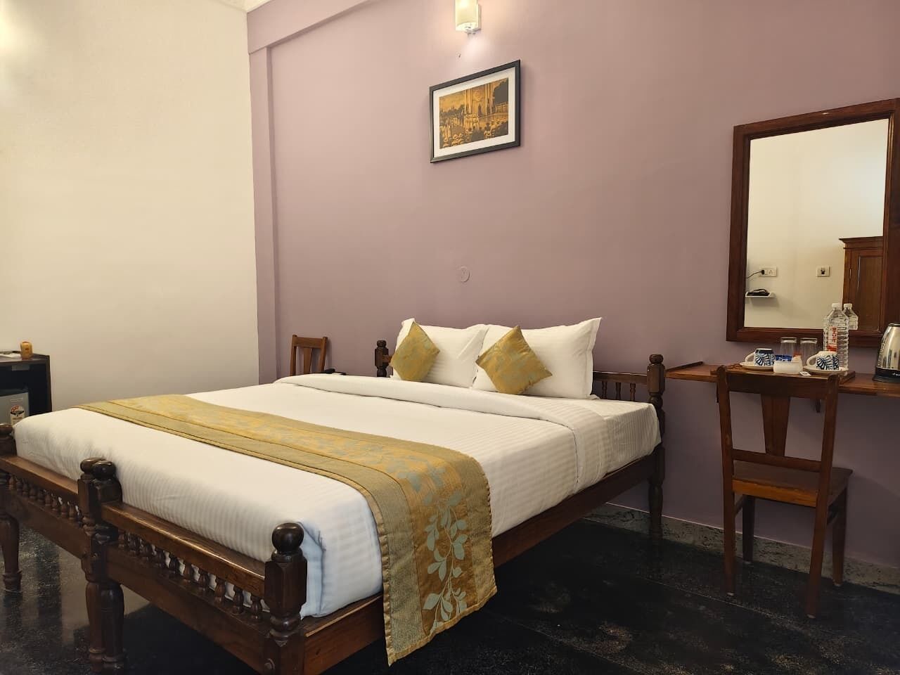 A neatly made bed with a wooden frame, a bedside table with a lamp, and a mirror on the wall.