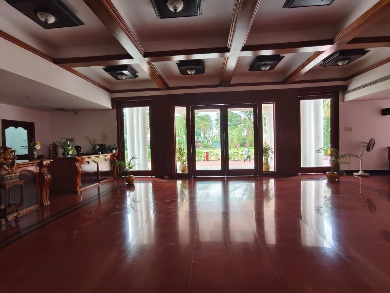 A spacious lobby with a polished wooden floor, large windows, and a reception desk.