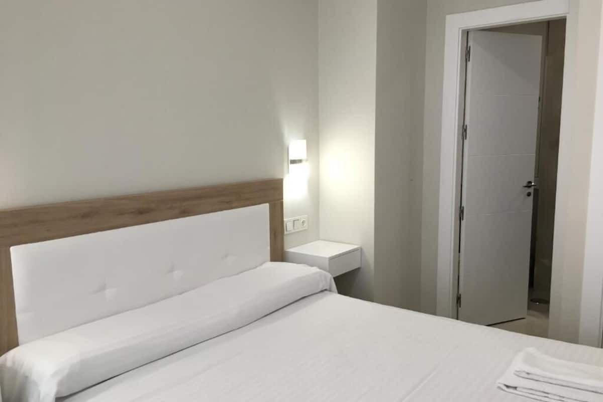Une chambre d’hôtel avec un lit, une table de chevet et une porte.