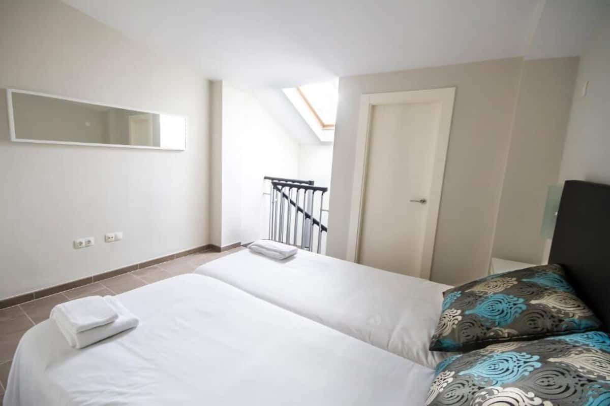 Une chambre à coucher avec un lit, une fenêtre, une porte et un petit balcon.