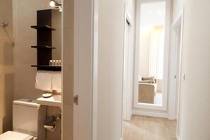 A modern bathroom with a toilet, a shelf with toiletries, and a towel hanging on the wall. - Apartamentos Pinar Málaga Centro (Málaga)
