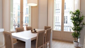 A dining area with a white table and chairs, a hanging light fixture, and a potted plant. - Apartamentos Pinar Málaga Centro (Málaga)