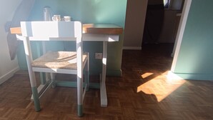 Una habitación con piso de madera, una silla blanca con asiento tejido y una pared azul claro.